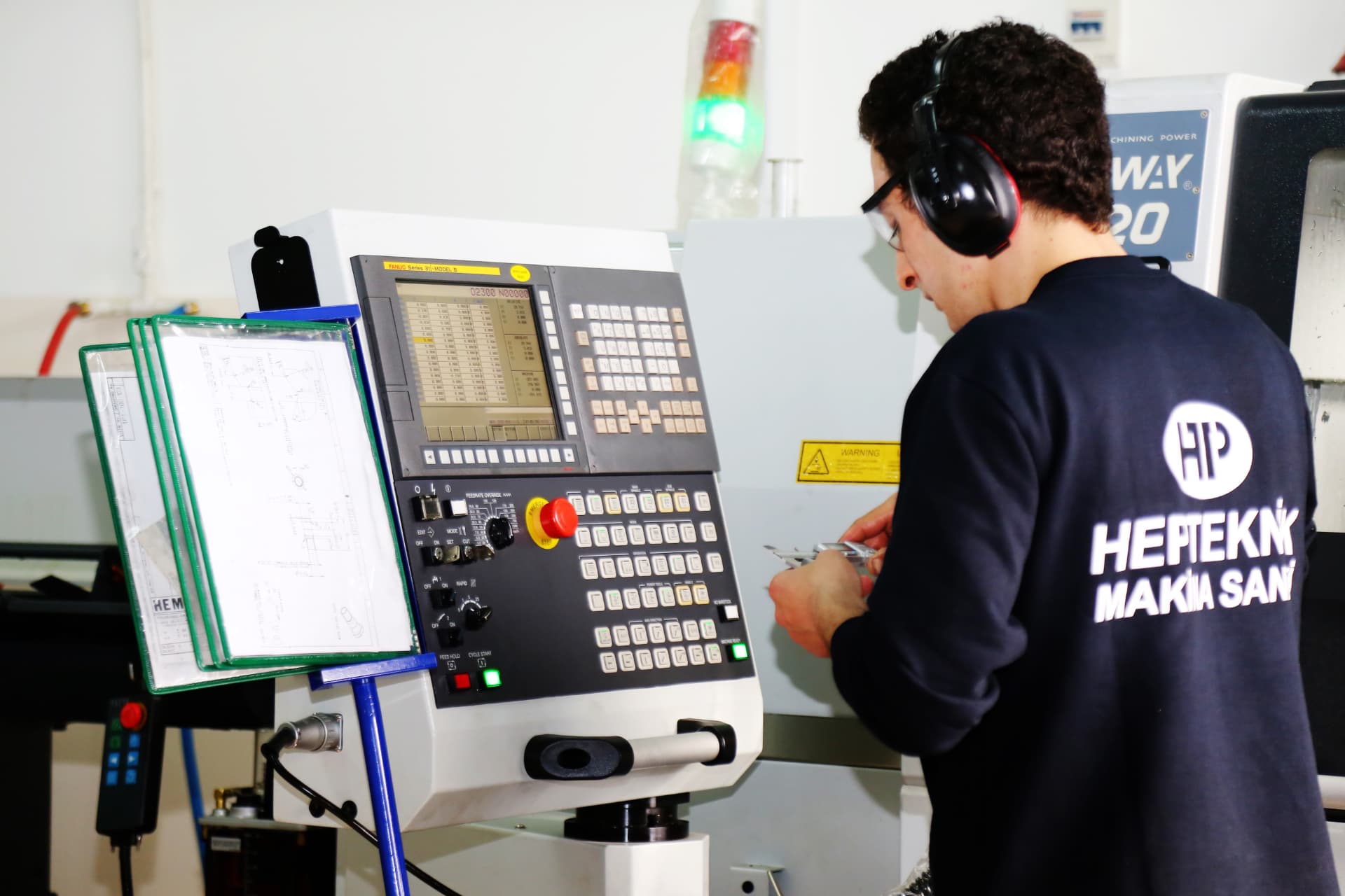 In-process caliper inspection next to a Swiss-type CNC machine at HEPTEKNIK